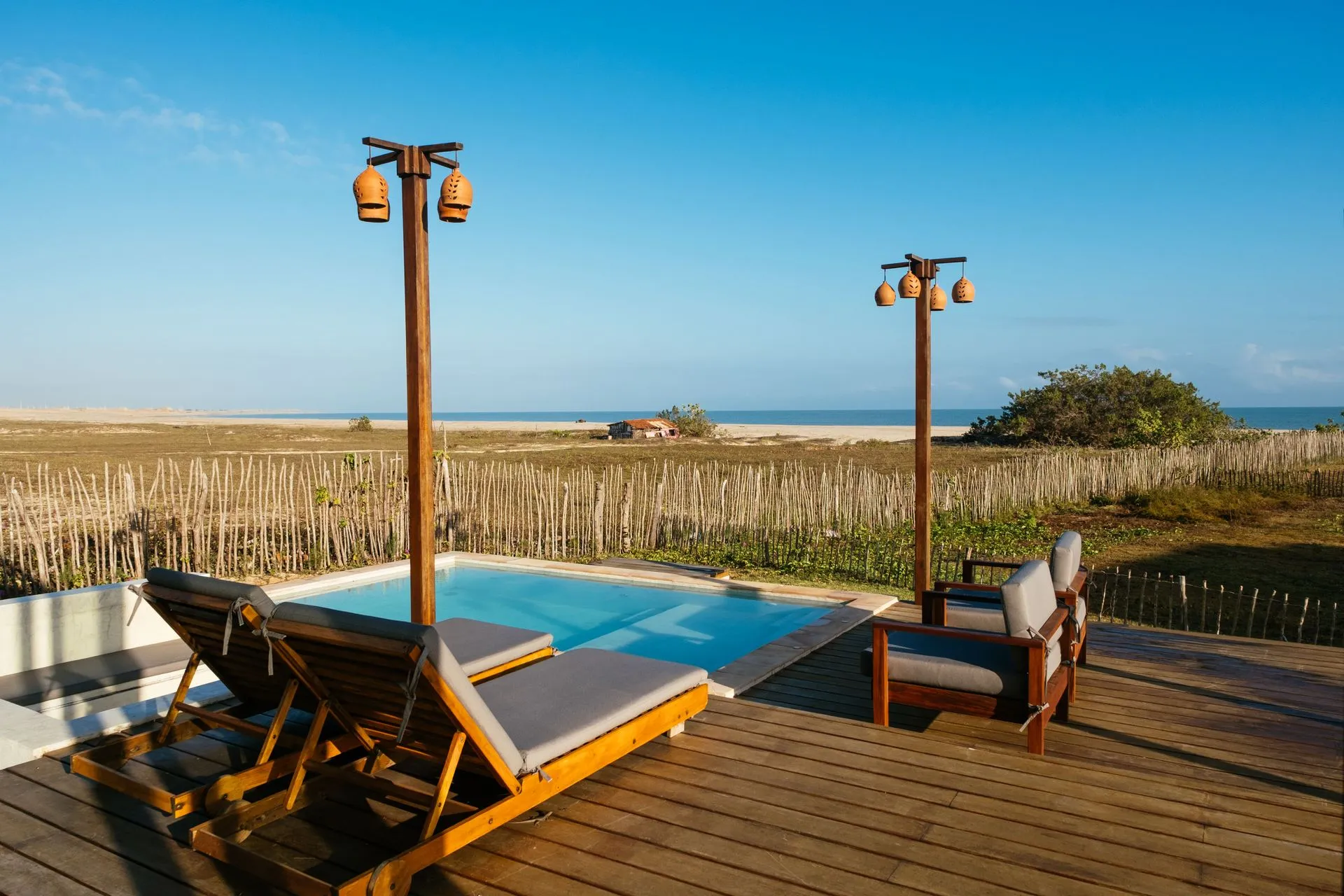 Deck de madeira com espreguiçadeiras e piscina privativa de frente para a praia
